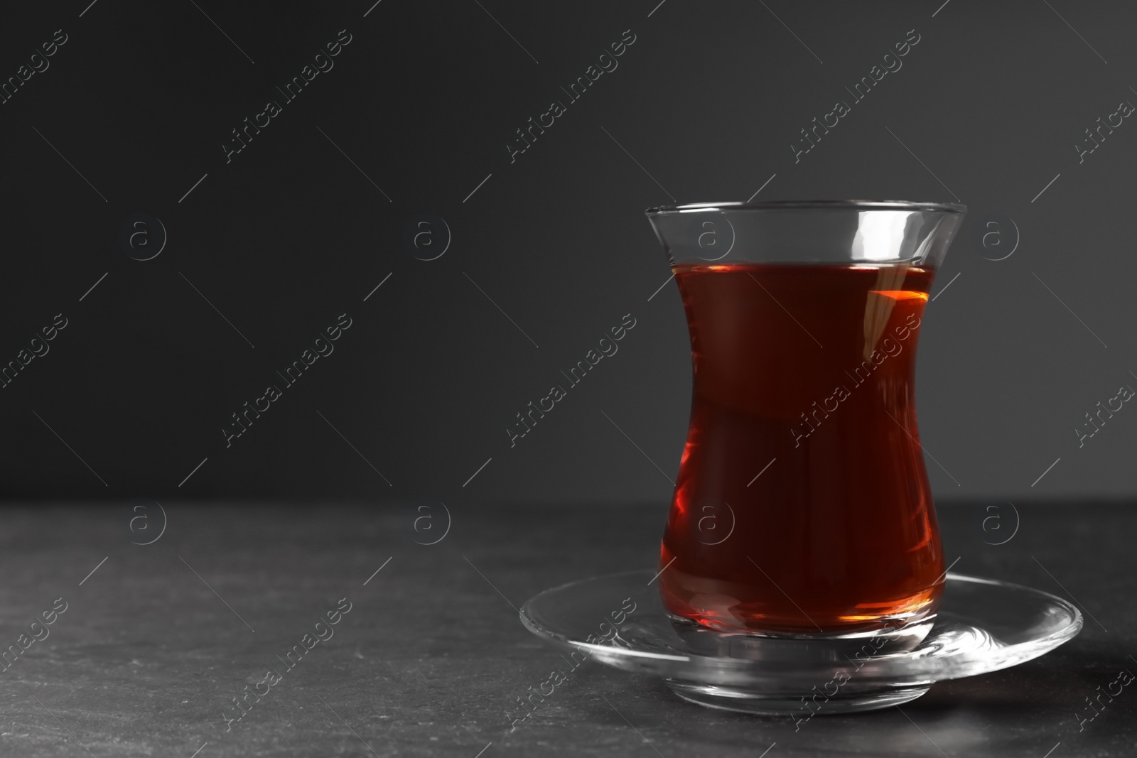 Photo of Glass with traditional Turkish tea on black table. Space for text