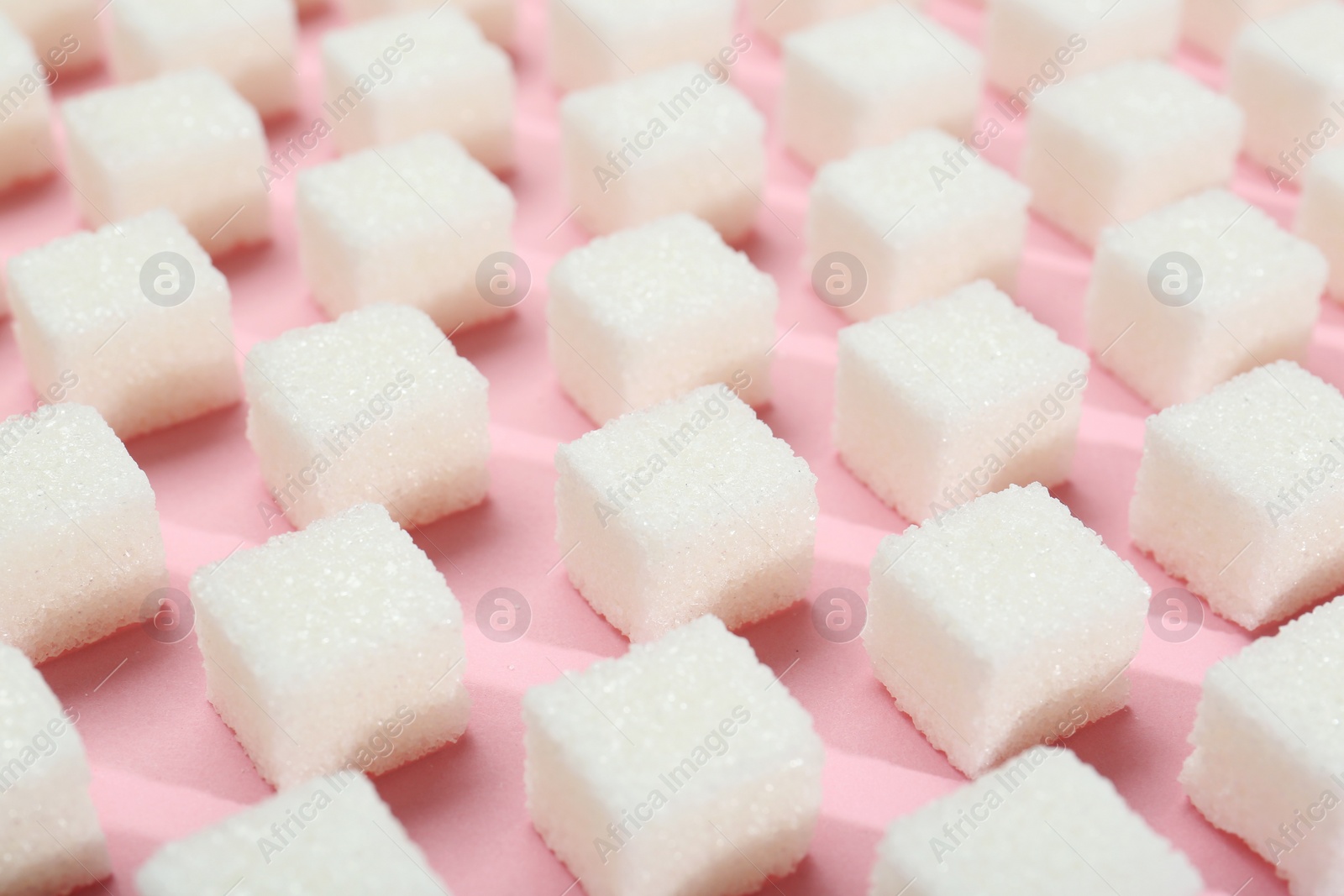 Photo of White sugar cubes on pink background, closeup