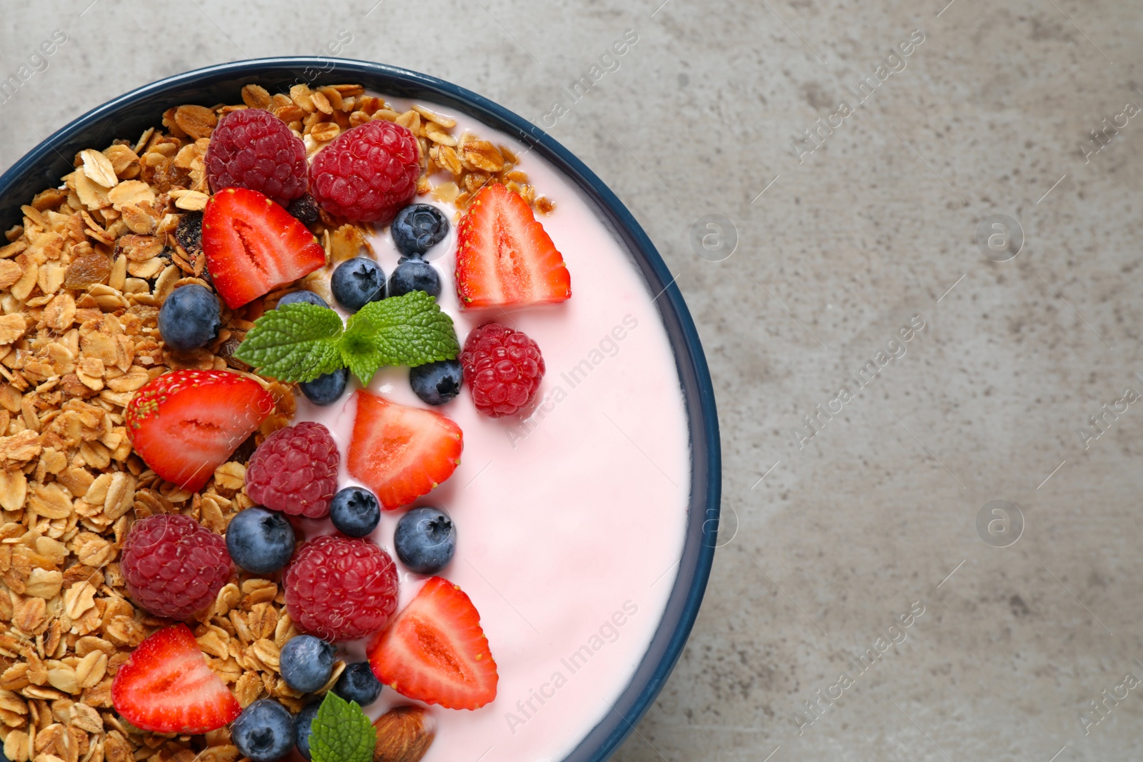 Photo of Tasty homemade granola with yogurt on grey table, top view. Healthy breakfast