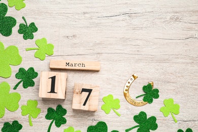 Flat lay composition with block calendar on white wooden table, space for text. Saint Patrick's Day celebration