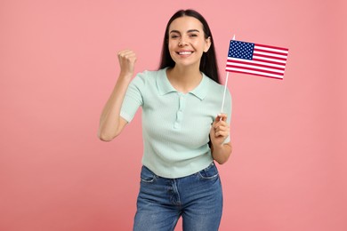 Happy young woman with flag of USA on pink background