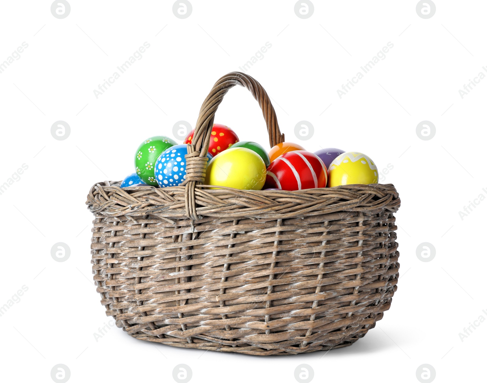 Photo of Decorated Easter eggs in wicker basket on white background