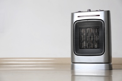 Modern electric fan heater on floor in room, space for text