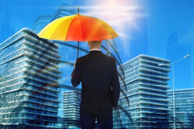 Image of Businessman with umbrella in city center on sunny day. Insurance concept