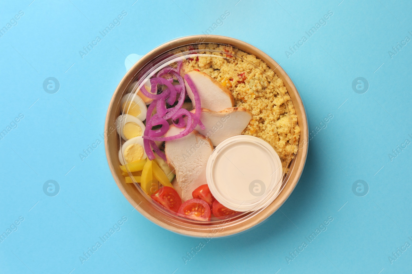 Photo of Tasty food in container on light blue background, top view