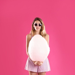 Photo of Emotional young woman with cotton candy on pink background