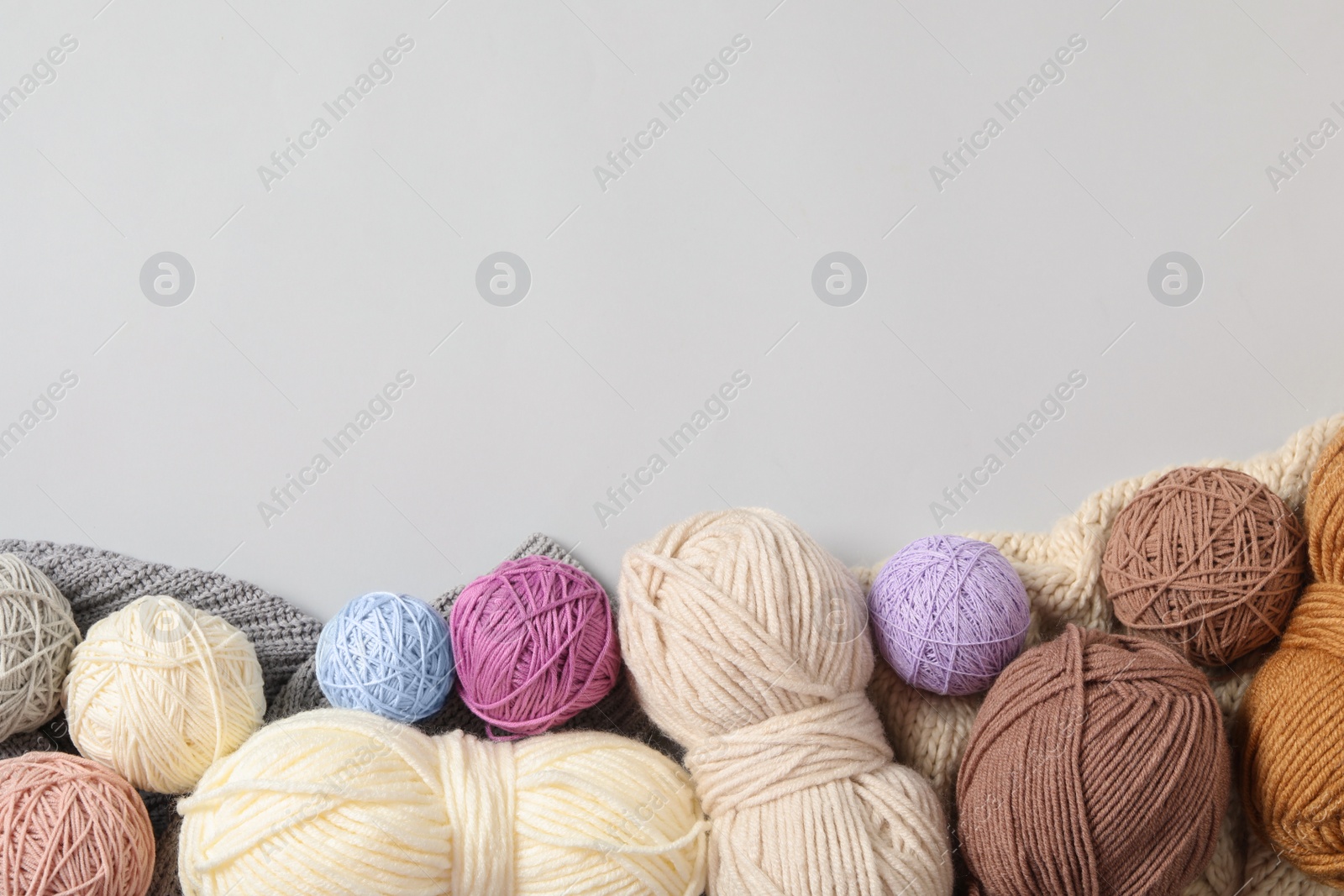 Photo of Soft colorful woolen yarns on white background, flat lay. Space for text