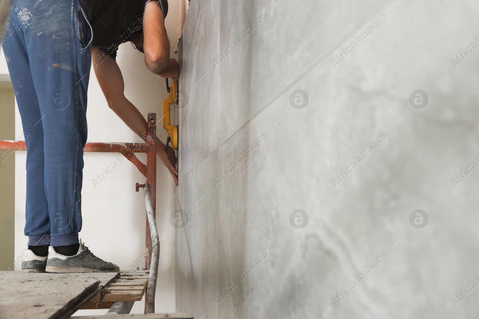 Photo of Worker installing new wall tile indoors. Prepared for renovation