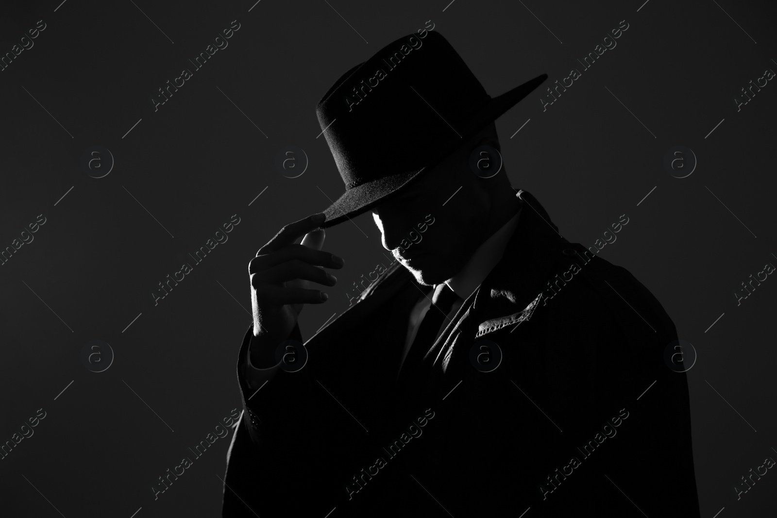 Photo of Old fashioned detective in hat on dark background, black and white effect