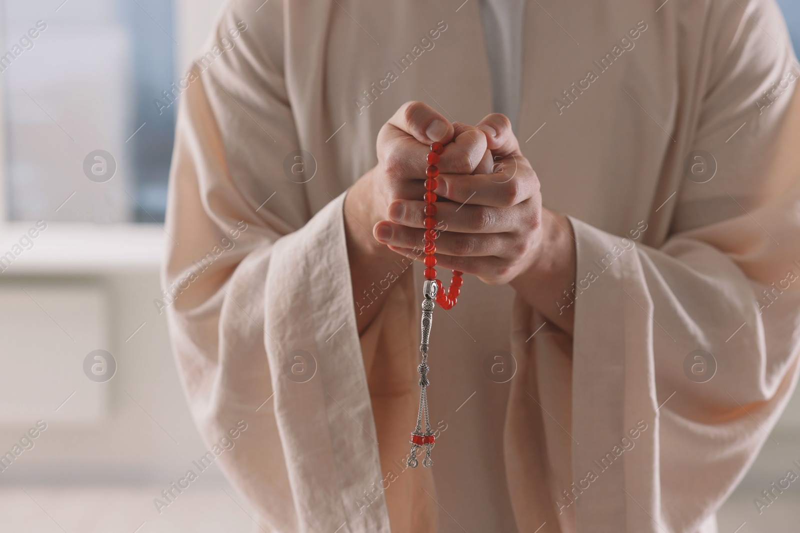 Photo of Muslim man with misbaha near window indoors, closeup. Space for text