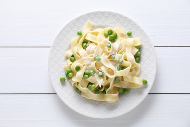 Photo of Delicious pasta with green peas on white wooden table, top view