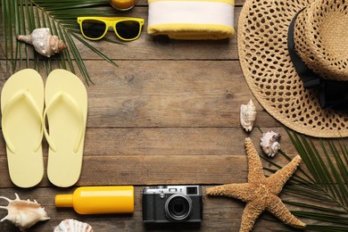 Frame of different beach objects on wooden background, flat lay. Space for text