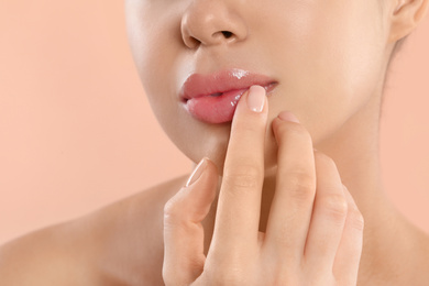 Photo of Young woman with beautiful full lips on peach background, closeup