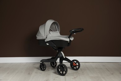 Photo of Baby carriage. Modern pram near brown wall