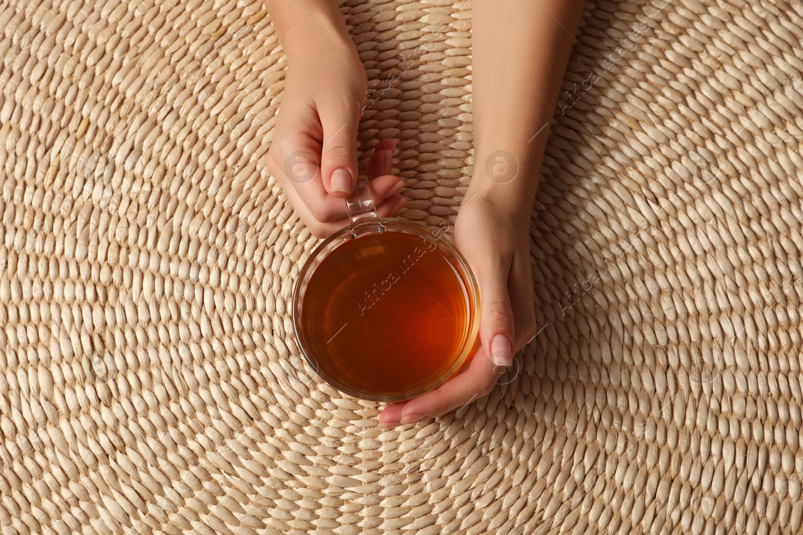 Photo of Woman with cup of black tea at wicker table, top view