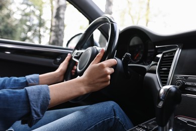 Photo of Woman holding steering wheel while driving her car, closeup