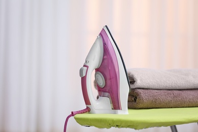 Photo of Modern iron and towels on board against blurred background. Space for text