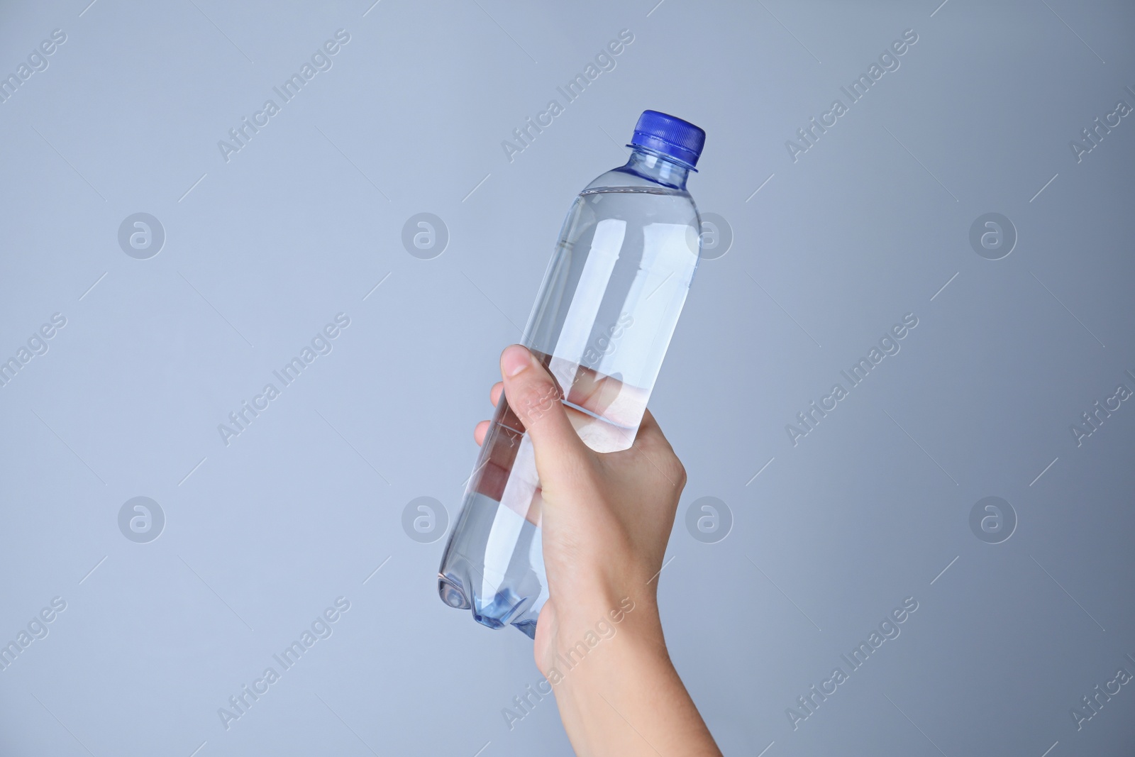 Photo of Woman holding plastic bottle with water on white background, closeup