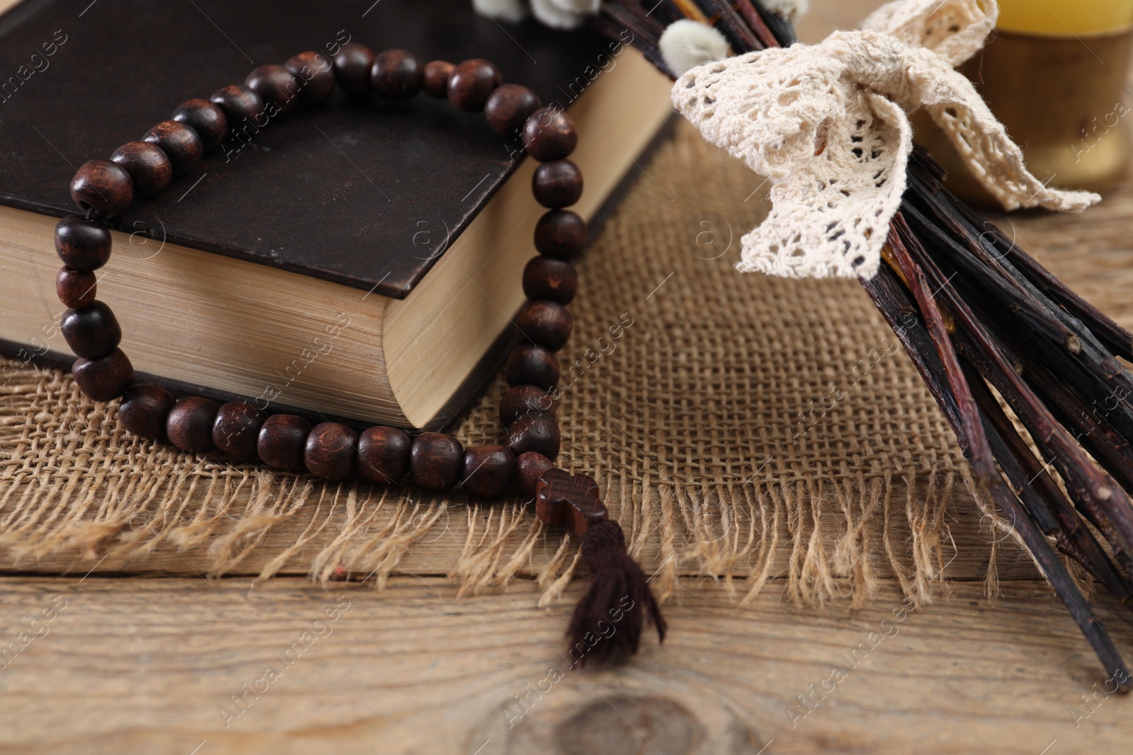 Photo of Rosary beads, Bible and willow branches on wooden table, closeup