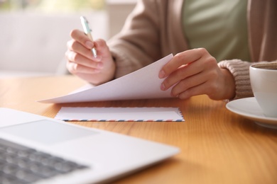 Photo of Woman writing letter at wooden table, closeup