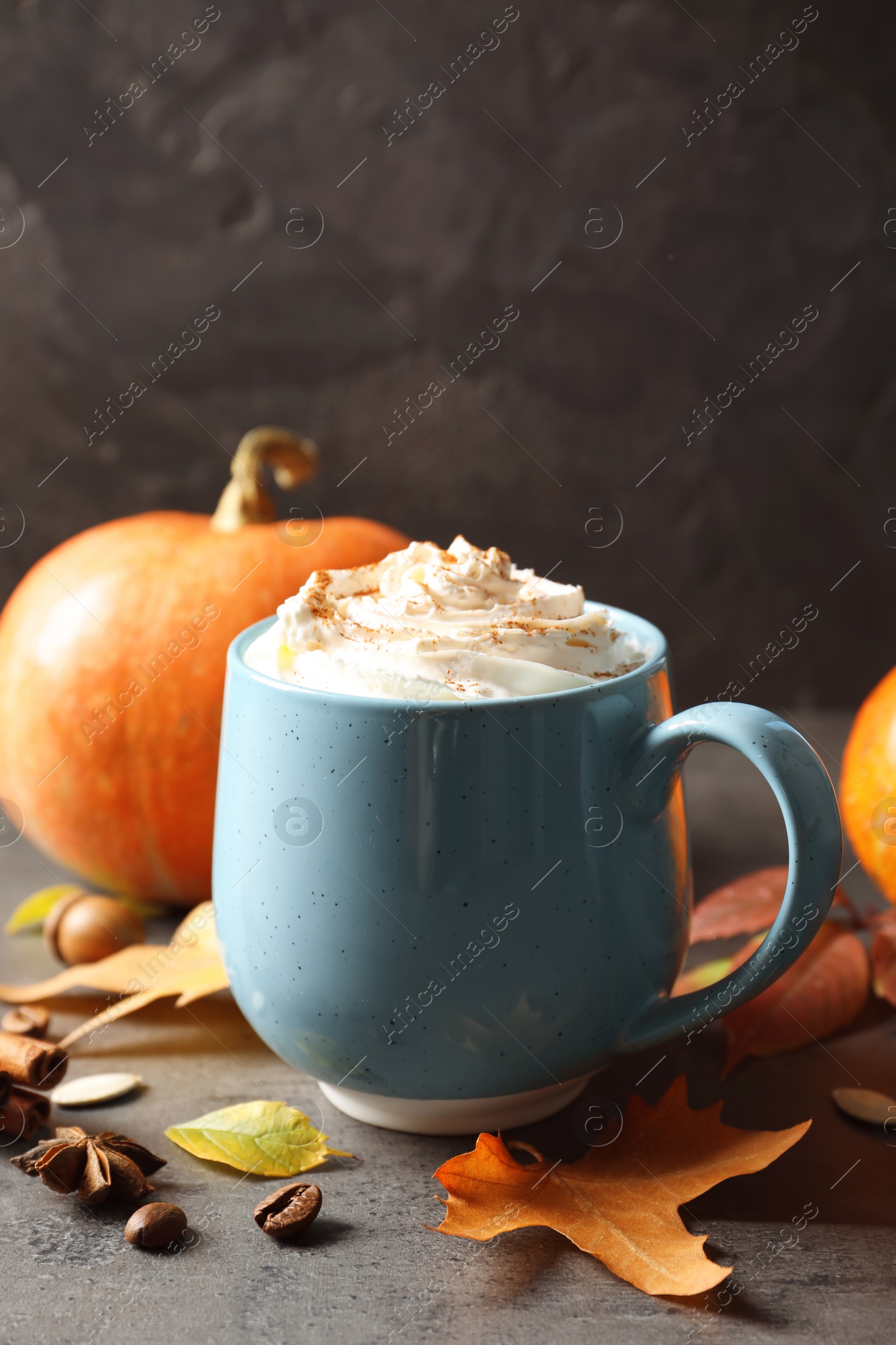 Photo of Cup with pumpkin spice latte on gray table. Space for text