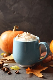 Cup with pumpkin spice latte on gray table. Space for text