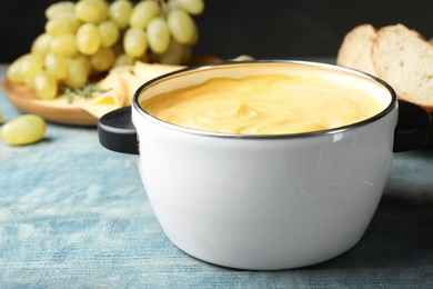 Photo of Pot with delicious cheese fondue on wooden table