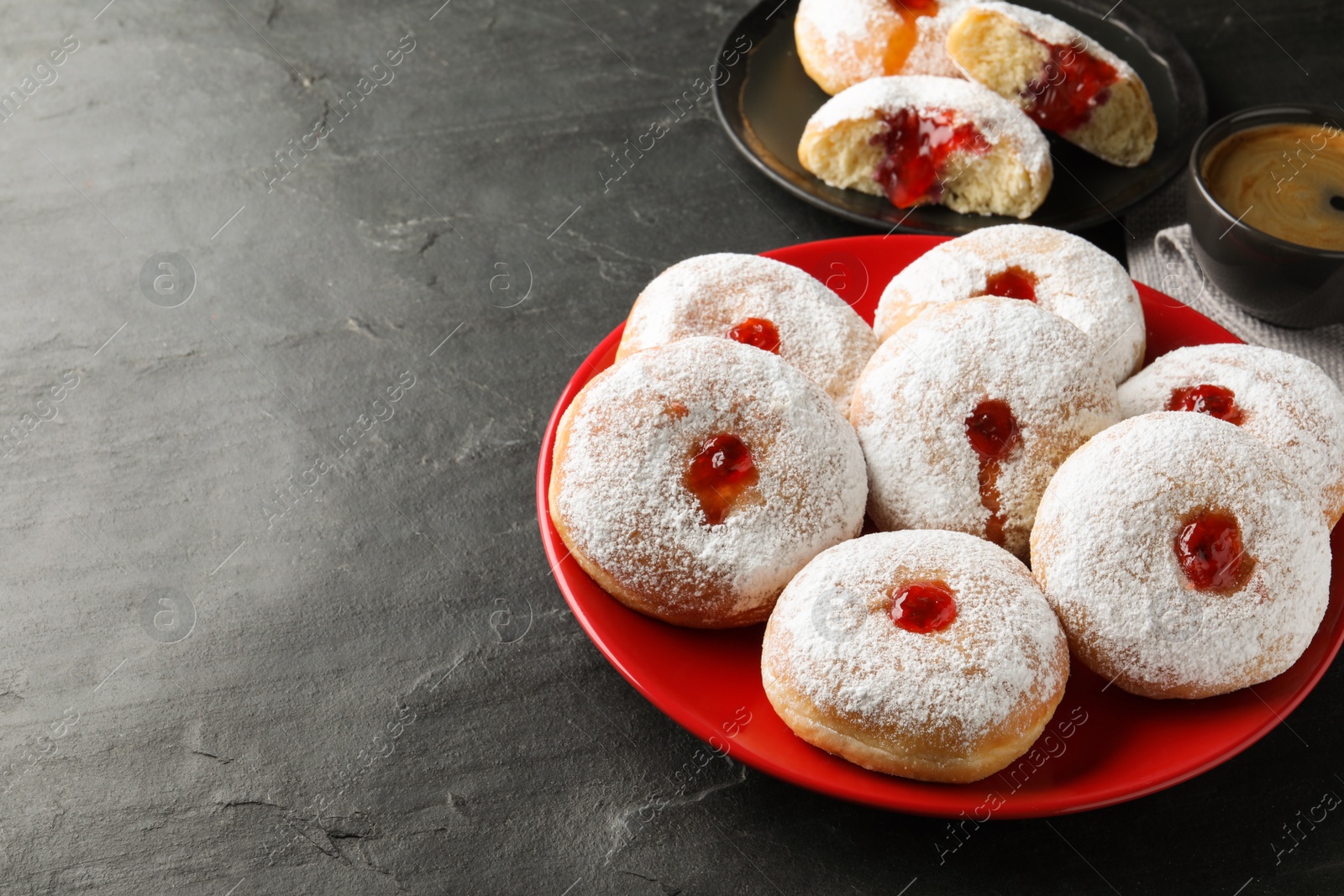 Photo of Delicious donuts with jelly and powdered sugar on black table. Space for text