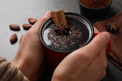 Photo of Woman with mug of yummy hot chocolate at grey table, closeup