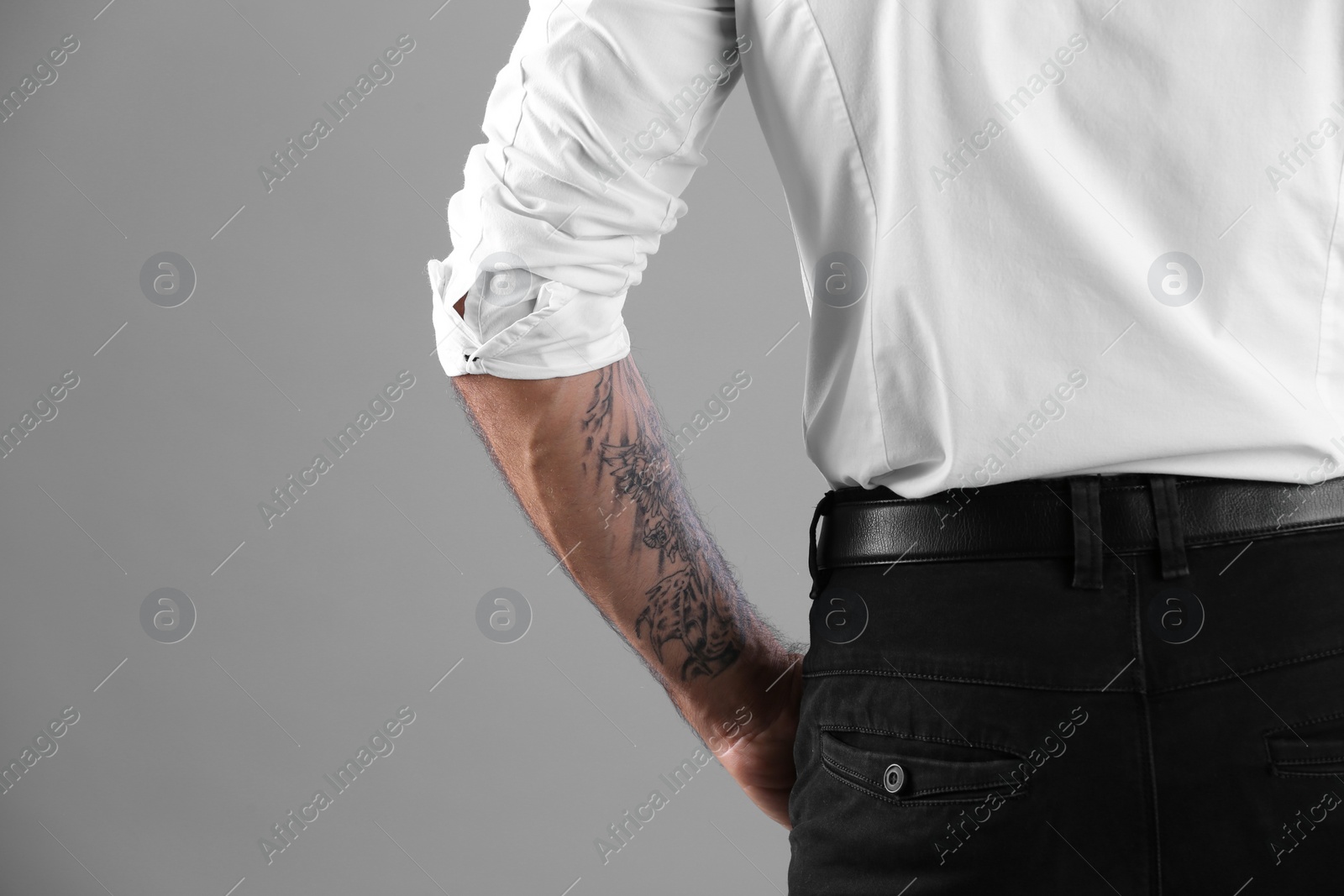 Photo of Tattooed man on grey background, closeup view. Space for text