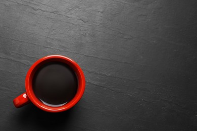 Photo of Red cup with aromatic coffee on black textured table, top view. Space for text