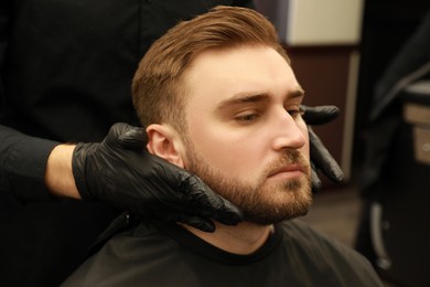 Professional hairdresser working with client in barbershop