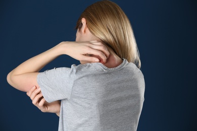Photo of Woman scratching neck on color background. Allergy symptom