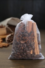 Photo of Scented sachet with coffee beans, anise and cinnamon on wooden table, closeup