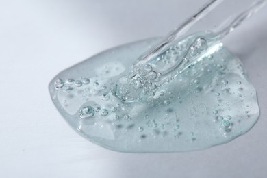 Photo of Pipette with cosmetic serum on white background, closeup