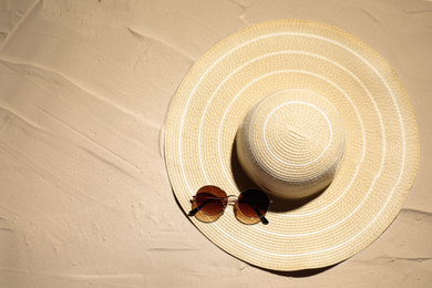 Hat and sunglasses on sand, top view. Beach accessories