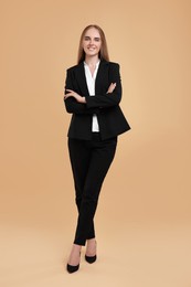 Photo of Happy young secretary with crossed arms on beige background