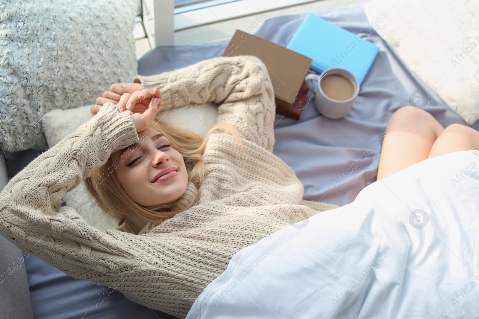 Photo of Beautiful young woman awaking and smiling at home, top view. Winter atmosphere