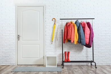 Rack with stylish warm jackets in hallway