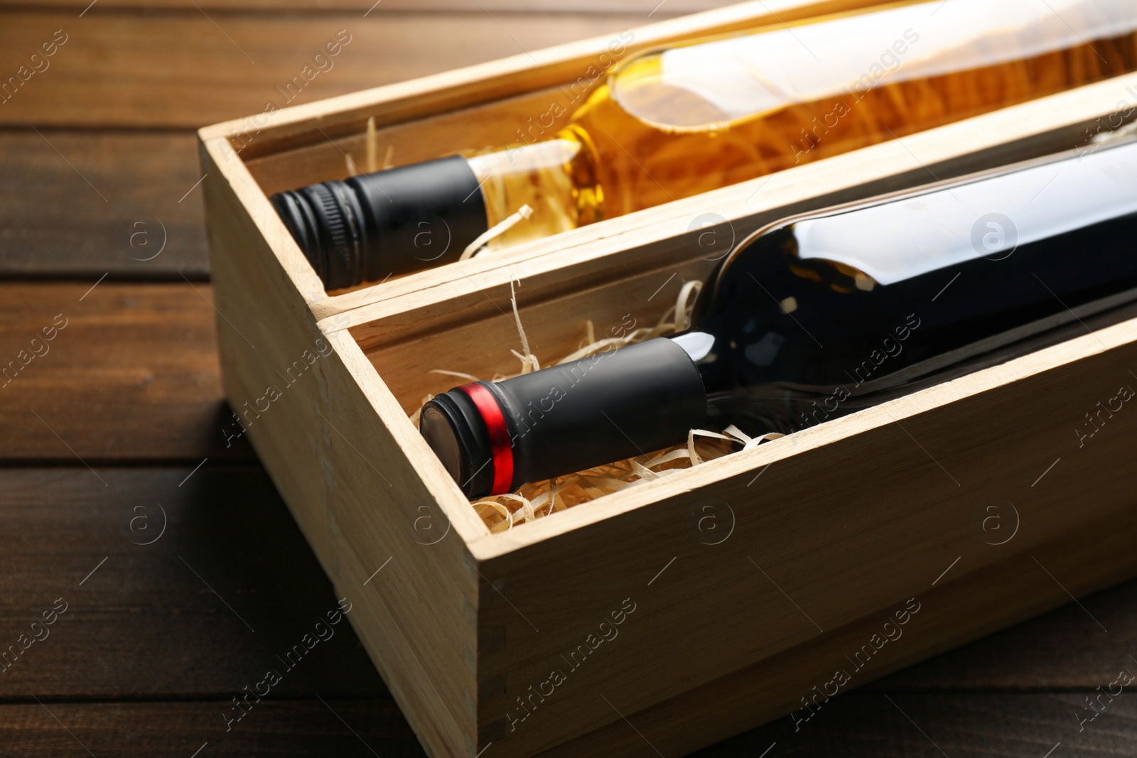 Photo of Boxes with bottles of wine on wooden background, closeup