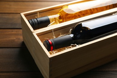 Photo of Boxes with bottles of wine on wooden background, closeup