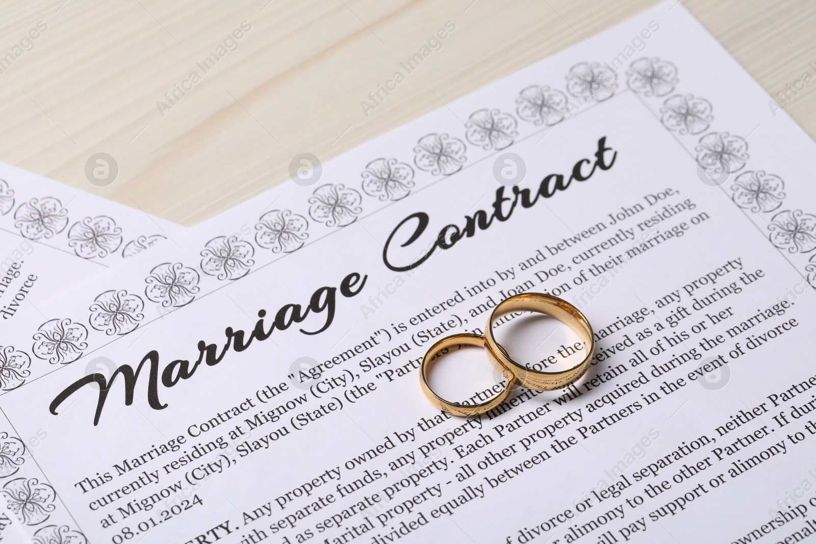 Photo of Marriage contracts and gold rings on light wooden table, closeup