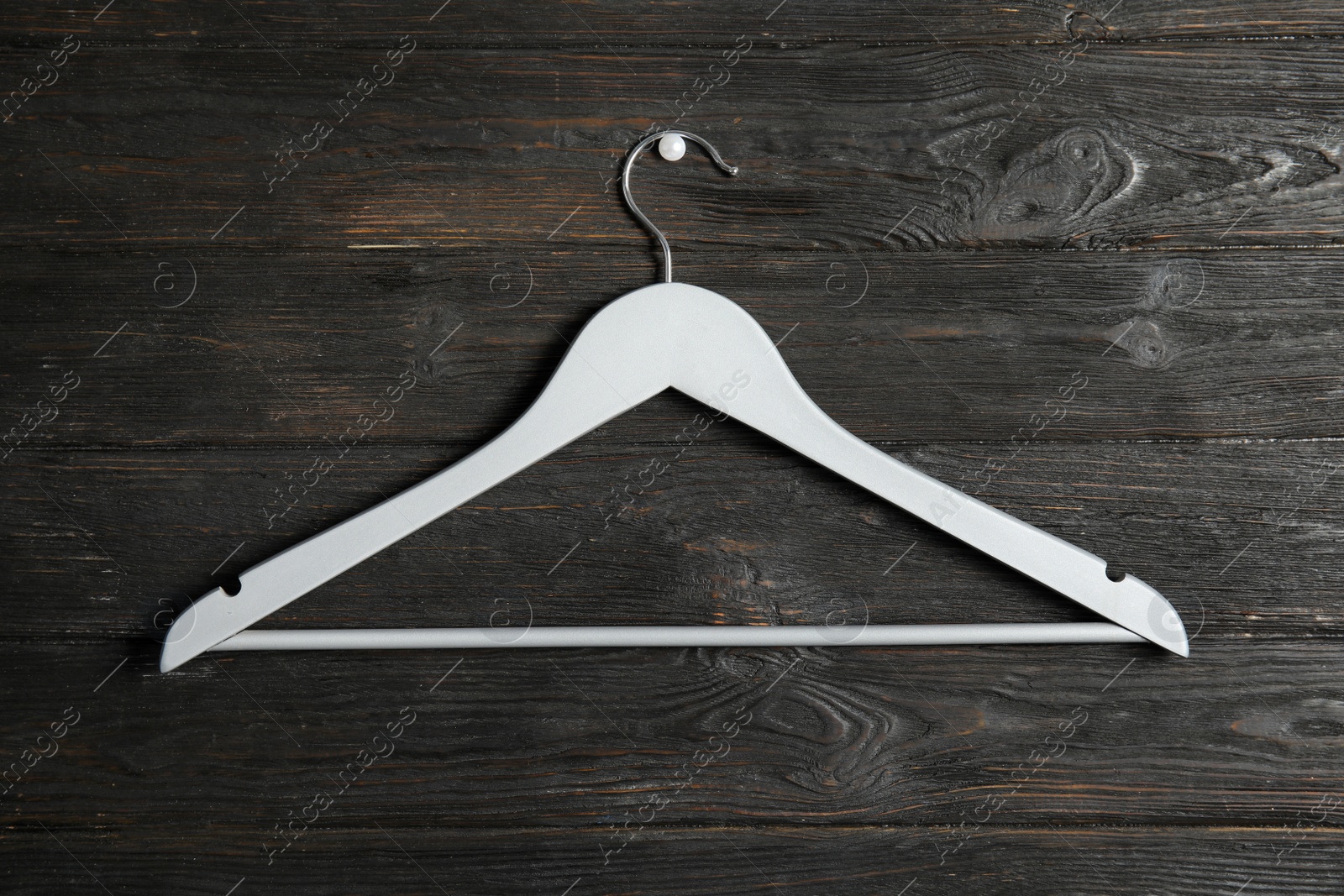 Photo of Empty clothes hanger on wooden wall. Wardrobe accessory