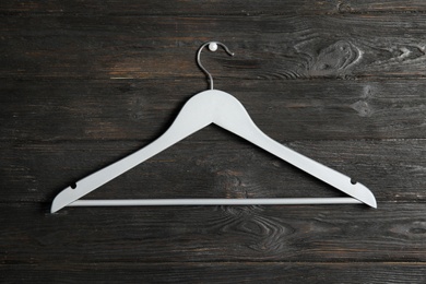 Photo of Empty clothes hanger on wooden wall. Wardrobe accessory