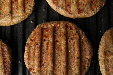 Photo of Delicious vegan cutlets cooking on electric grill, top view