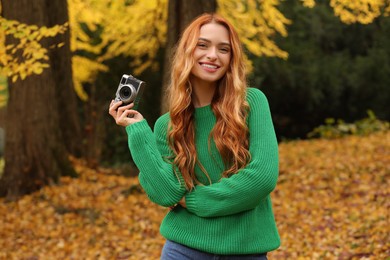 Photo of Smiling woman with camera in autumn park