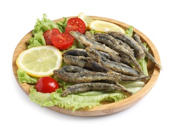 Wooden plate with delicious fried anchovies, lemon slices, tomatoes and lettuce leaves on white background
