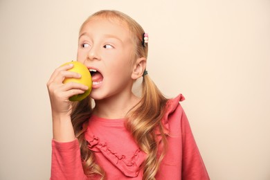 Cute little girl with apple on light background