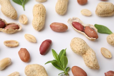 Photo of Fresh peanuts and leaves on white table, above view