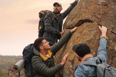 Photo of Group of hikers with backpacks climbing up mountains